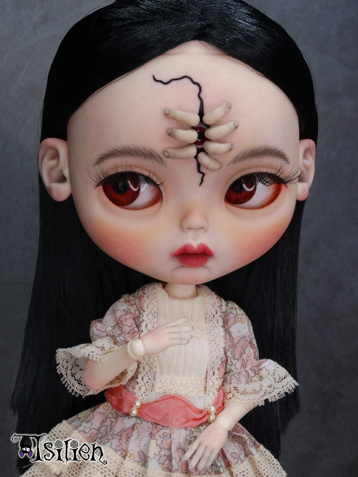 Amara, muñeca Blythe custom de aspecto siniestro y dulce, con pelo negro, vestido vintage y gorrito con orejas de conejo. Unos dedos abren una grieta en su frente, dejando ver un misterioso ojo.
