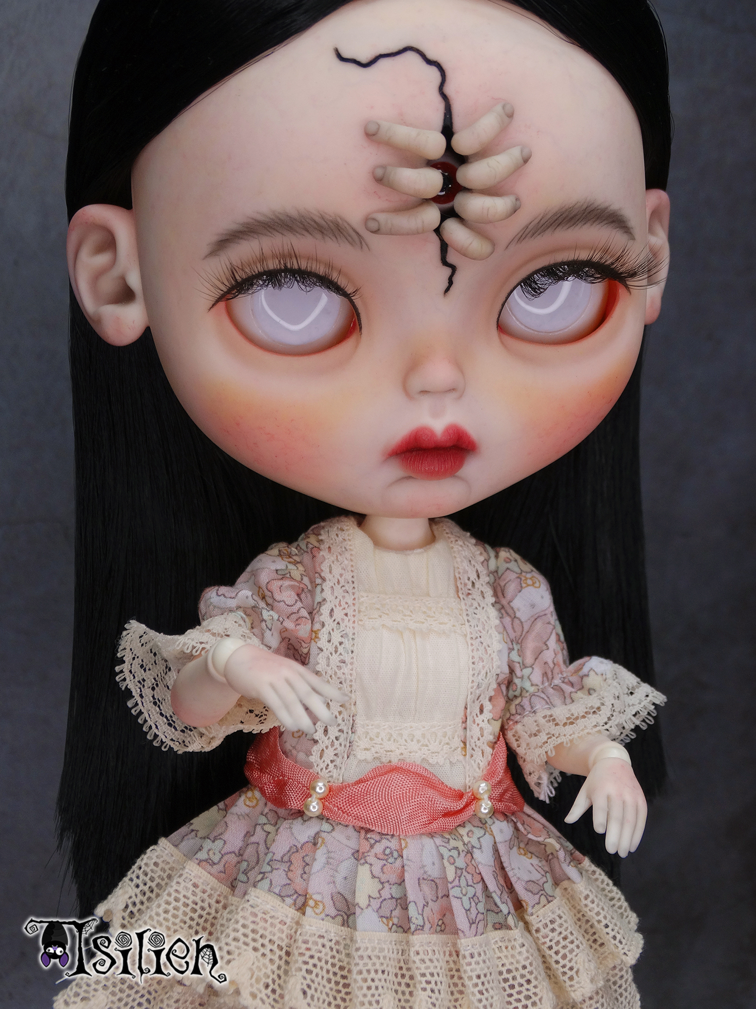 Amara, muñeca Blythe custom de aspecto siniestro y dulce, con pelo negro, vestido vintage y gorrito con orejas de conejo. Unos dedos abren una grieta en su frente, dejando ver un misterioso ojo.