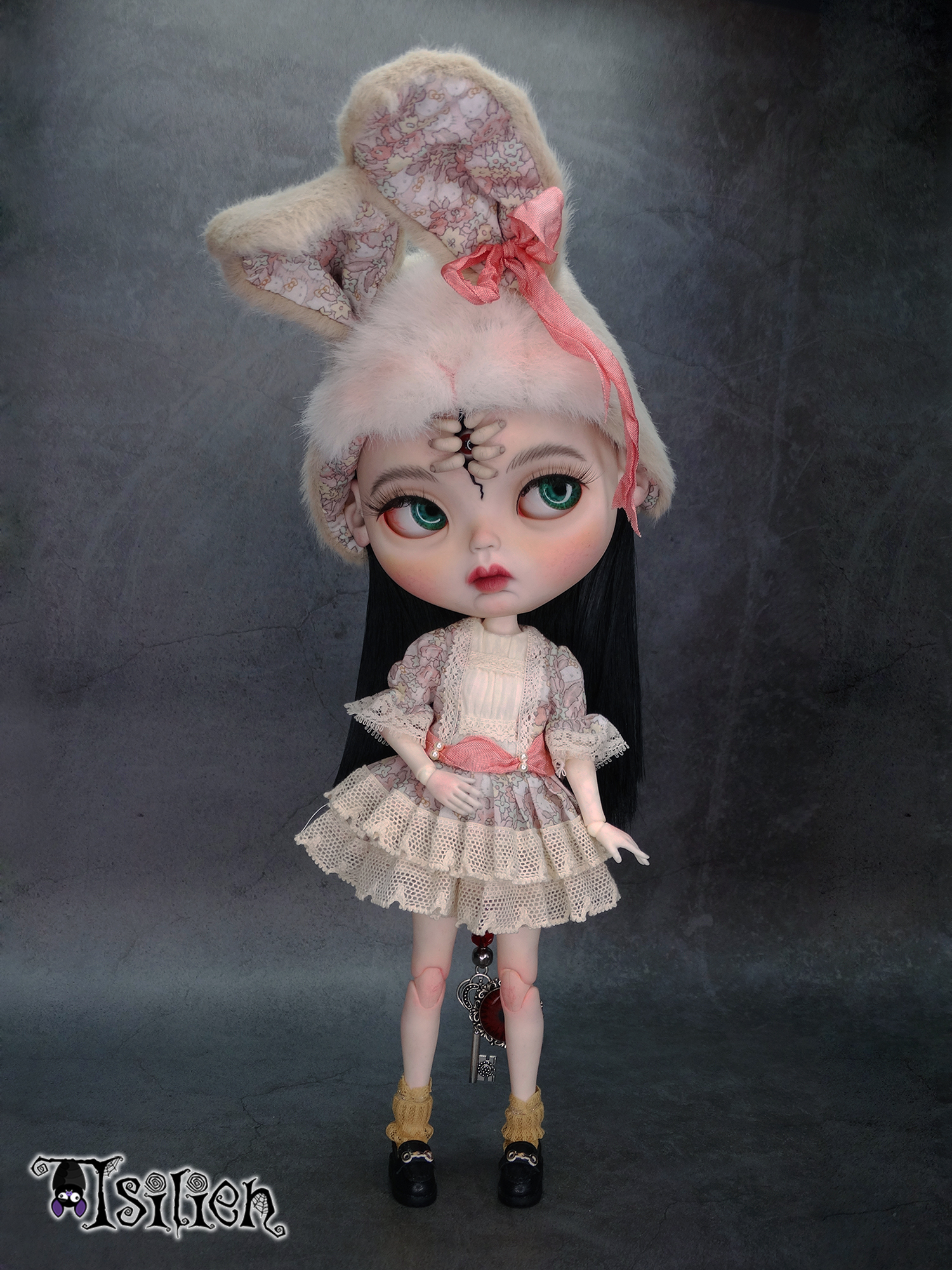 Amara, muñeca Blythe custom de aspecto siniestro y dulce, con pelo negro, vestido vintage y gorrito con orejas de conejo. Unos dedos abren una grieta en su frente, dejando ver un misterioso ojo.