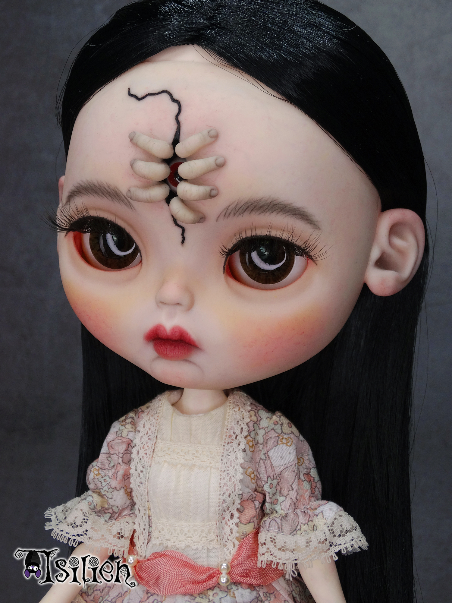 Amara, muñeca Blythe custom de aspecto siniestro y dulce, con pelo negro, vestido vintage y gorrito con orejas de conejo. Unos dedos abren una grieta en su frente, dejando ver un misterioso ojo.